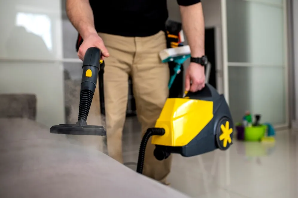 Person using a yellow steam cleaner on a hard floor