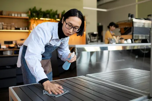 Cleaner wiping down a counter in a cafe kitchen