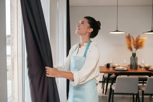 Cleaner hanging curtains in a dining room