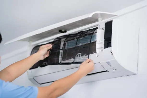 Hands opening the filter cover of a wall-mounted air conditioner