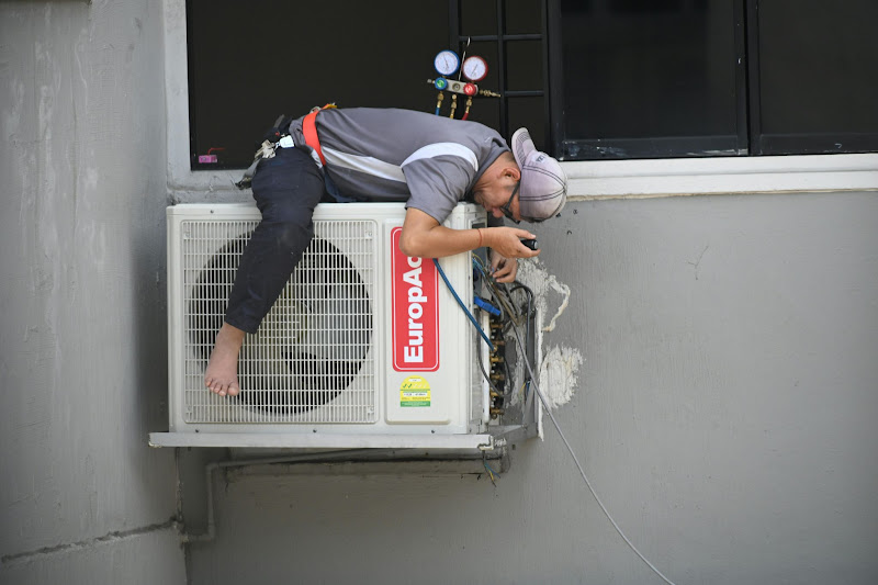 A man doing a repair for an aircon because of a leaking water.