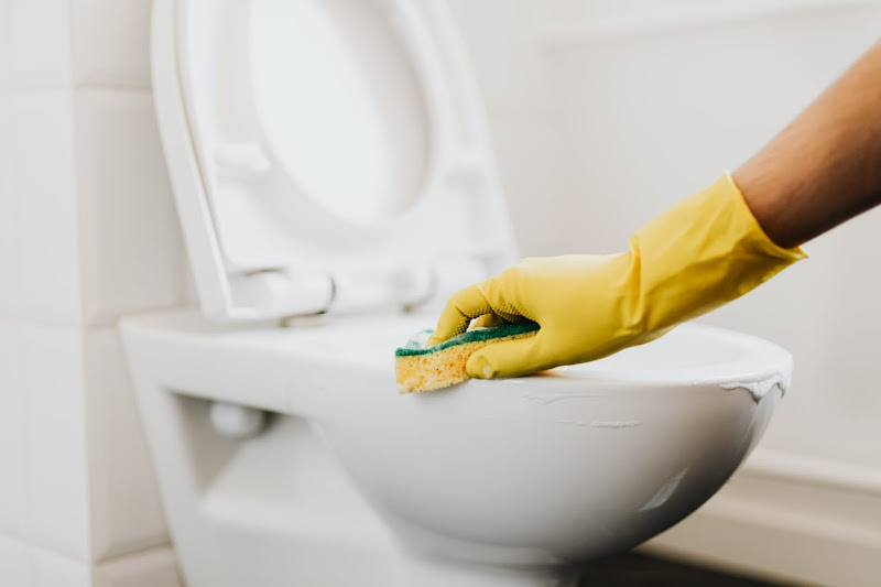 A man giving cleaning services on a client's bathroom.